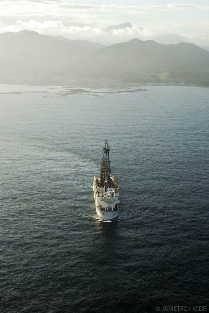 Chikyu vessel in open ocean. Mountains in background. 