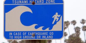 A blue and white sign to warn beachgoers that they are in a tsunami hazard zone. Credit: debaird from So California, CC BY-SA 2.0